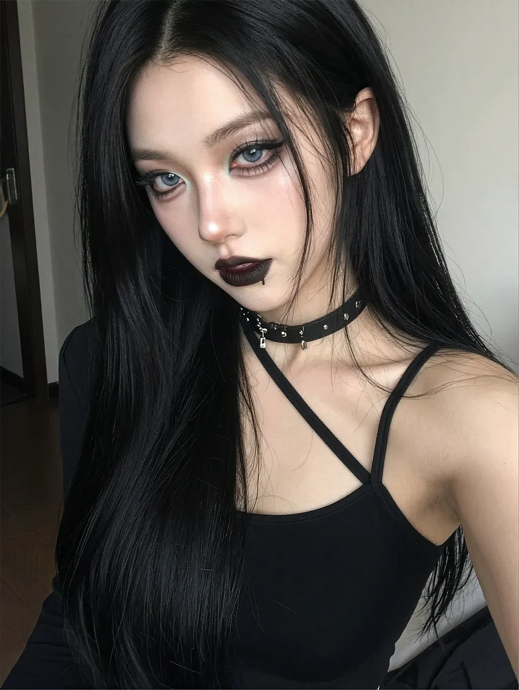 Fictional AI character with black hair, black lipstick and a strappy black top